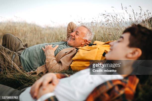 glücklicher großvater und enkel entspannen auf einem picknick - teenager alter stock-fotos und bilder