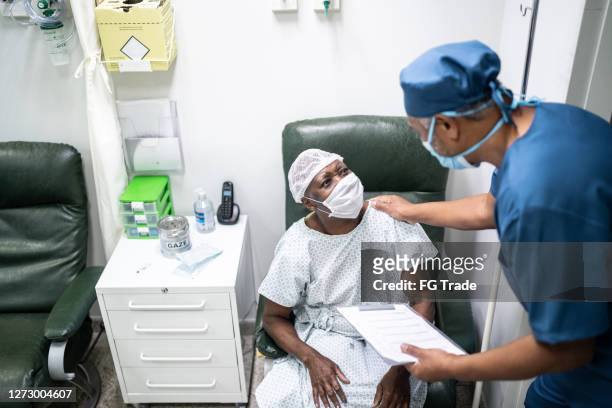 Nurse talking and doing a emotional support to a female senior patient at hospital - wearing face mask