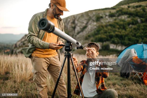 vater und sohn mit teleskop auf campingplatz - fernrohr stock-fotos und bilder