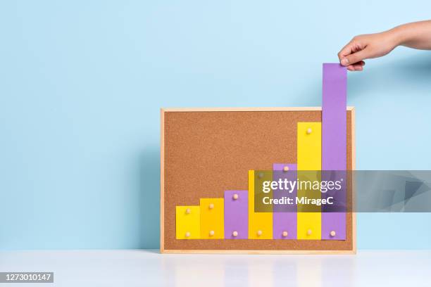 hand pulling up rising bar chart - high angle view stockfoto's en -beelden