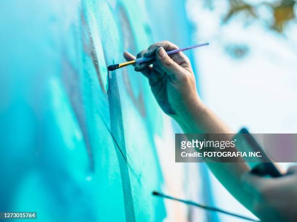 hand der weiblichen wandbild-künstlerin bei der arbeit - artist painting stock-fotos und bilder