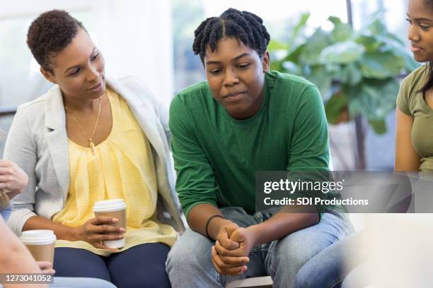 mom encourages teen as he shares in therapy group - serious teenager boy imagens e fotografias de stock