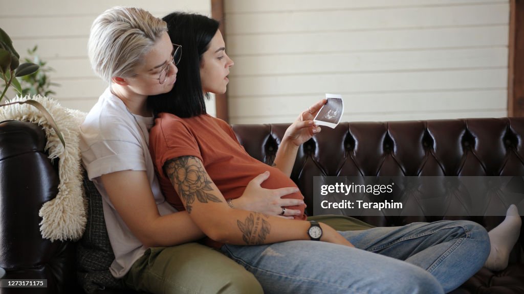 Blonde runs hands on pregnant girlfriend belly at home