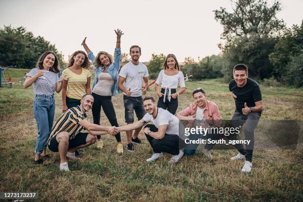 group photo of young happy volunteers outdoors - organised group photo stock pictures, royalty-free photos & images
