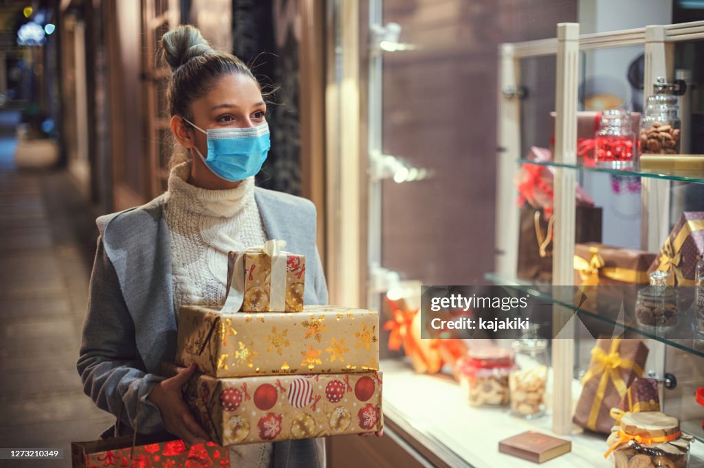 Teenage girl shopping Christmas gifts during COVID-19 pandemic. She wears a protective mask to protect from corona virus COVID-19.