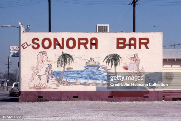 El Sonora Bar in Long Beach, California has a tropical scene of women in bathing suits on a beach painted on its facade, 1990.