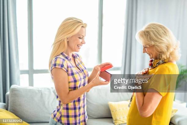 happy young woman giving a gift to her mother. - s dear mama event stock pictures, royalty-free photos & images