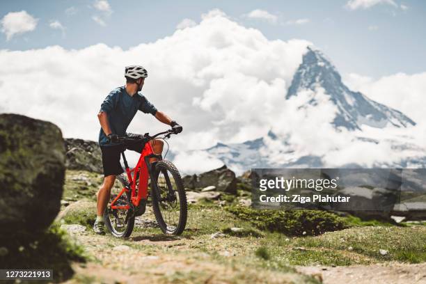 mountainbiker blickt auf majestätischen blick auf das matterhorn zurück - motorradfahrer stock-fotos und bilder