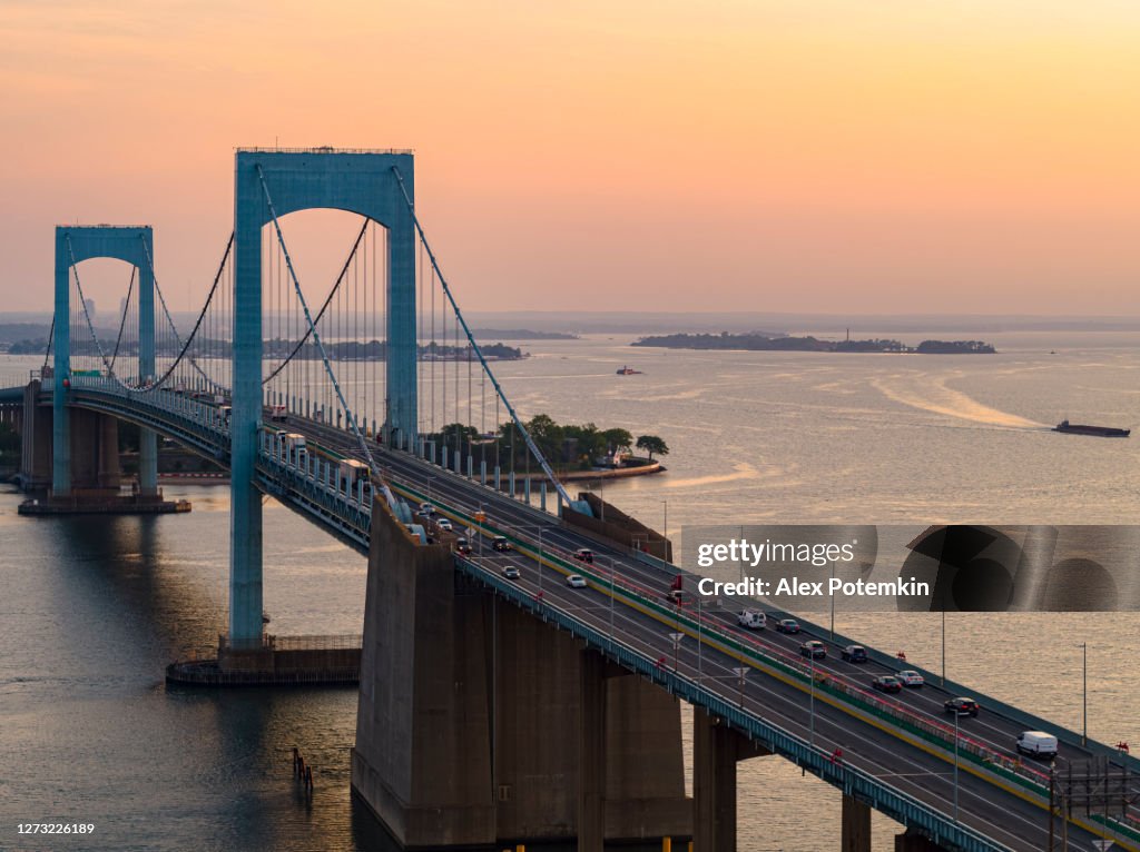 Mäßiger Verkehr auf der Throgs Neck Bridge über den East River, der Queens und Bronx Boroughs, New York, bei Sonnenaufgang verbindet.