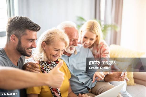 family surfing the net on laptop on sofa. - son in law stock pictures, royalty-free photos & images