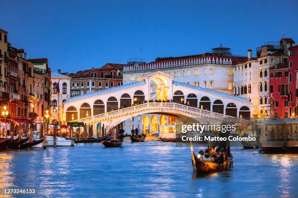 rialto bridge with gondola at night, venice, italy - rialto bridge foto e immagini stock