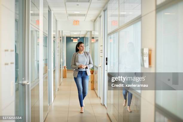 young hispanic businesswoman walking in coworking office - office hallway stock pictures, royalty-free photos & images