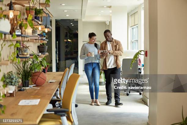 casual coworkers walking and using digital tablet in office - miami business imagens e fotografias de stock