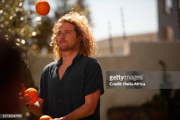 juggling performance of three oranges by young man - giocoliere foto e immagini stock