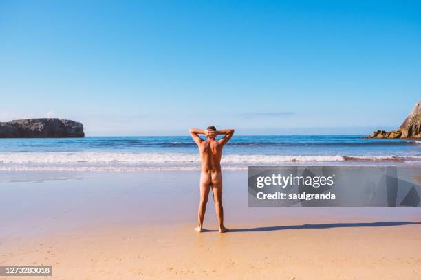 mid adult  man naked on a nudist beach, beach of torimbia, asturias, northern spain - beach bum imagens e fotografias de stock