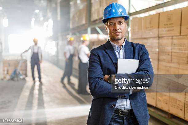 mid adult foreman with crossed arms in a warehouse. - gerente imagens e fotografias de stock
