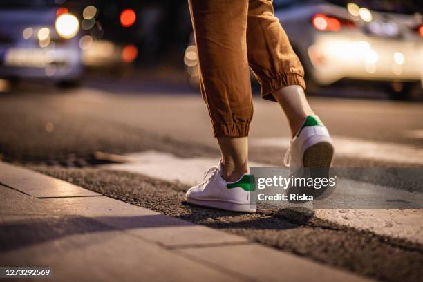 nahaufnahme menschlicher beine, die auf dem crosswalk laufen - laufschuhe stock-fotos und bilder