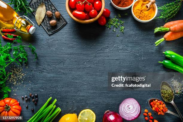 multi colored vegetables and spices frame on black slate background. overhead view - food table edge stock pictures, royalty-free photos & images