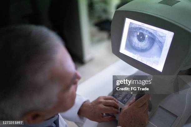 oogarts die de resultaten van het examen analyseert in een monitor - eye exam stockfoto's en -beelden