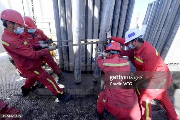 Employees of China National Petroleum Corporation work on an oil drilling rig at an oil well of Mahu Oilfield in Junggar Basinin on September 17,...