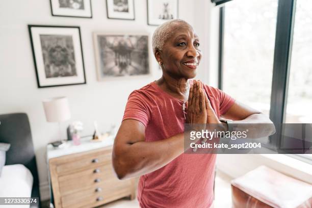 senior women taking care of her wellbeing, she is exercising at home in sportswear - baby boomer stock pictures, royalty-free photos & images