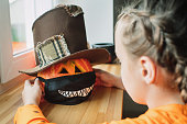 Child putting protective mask on Jack o'Lantern for Halloween