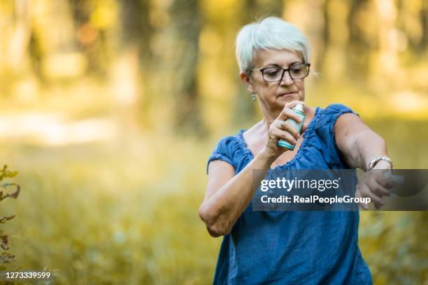 senior intheiseinsatz von insektenschutzmitteln im wald - insect bites images stock-fotos und bilder