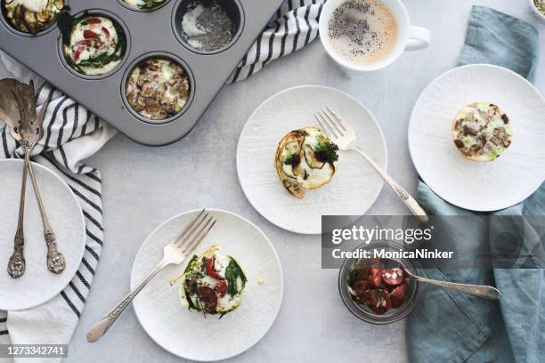 flat lay of muffin tin with baked vegetable mini egg white quiches served on plates - mini quiche stock pictures, royalty-free photos & images