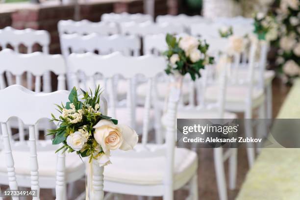 white wooden chairs decorated with flowers and bright satin ribbons, wedding decor at the ceremony. - venue stock pictures, royalty-free photos & images