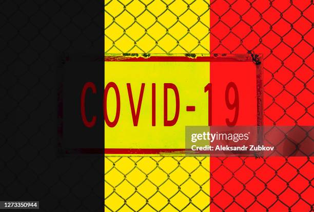 the flag of belgium is surrounded by a high metal wire fence with a banner and the inscription covid-19. the concept of closed borders of individual states and countries. - belgium border stock pictures, royalty-free photos & images