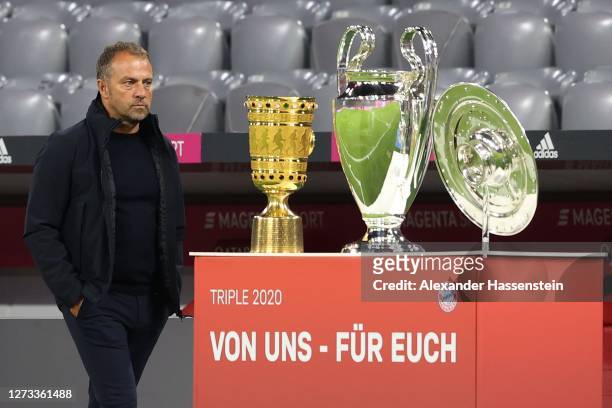 Hans-Dieter Flick, head coach of Munich walks next to the German Cup winners trophy, the Championsleague winners trophy and the German Championship...