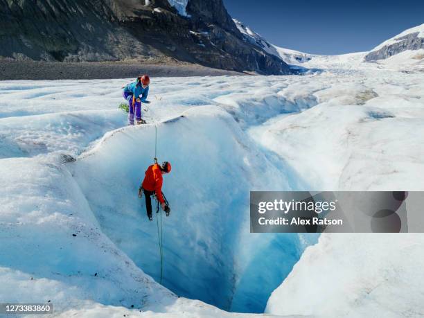 ice climber climbing out of deep crevasse on athabasca glacier - mountaineering team stock pictures, royalty-free photos & images