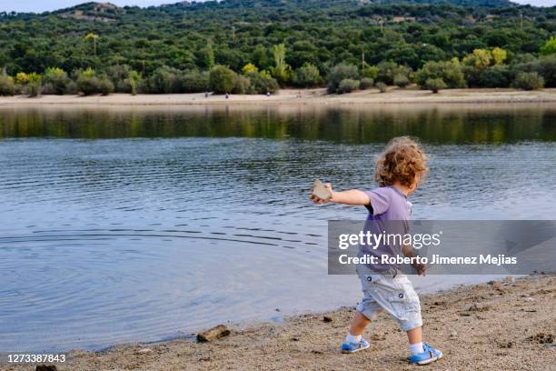 child throwing stones into a lake - throwing rocks stock pictures, royalty-free photos & images