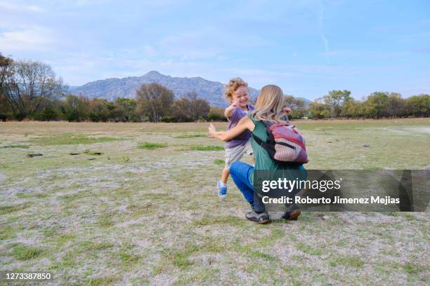 mother catching her son running up - open arms hug stock pictures, royalty-free photos & images