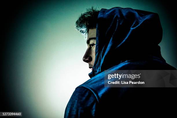 studio portrait of young adult male shot over shoulder and profile with hooded jacket. - alternative view portraits stock pictures, royalty-free photos & images