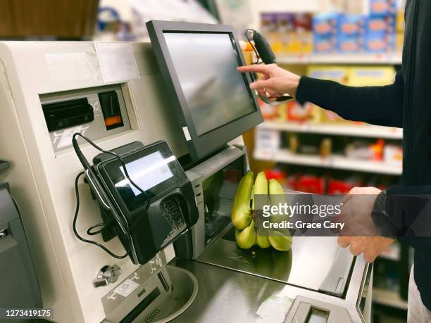 man purchases bananas at self-checkout kiosk - selbstbedienung stock-fotos und bilder