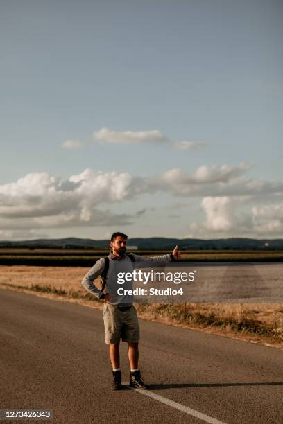 hipster hitchhiker en la carretera - hitchhiking fotografías e imágenes de stock