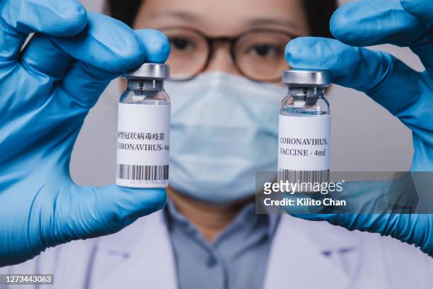 doctor or scientist looking at coronavirus vaccine with labels in english and chinese language - drug evaluation stock pictures, royalty-free photos & images