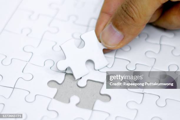hand holding white jigsaw puzzle will be matching. business concept. - unvollständig stock-fotos und bilder