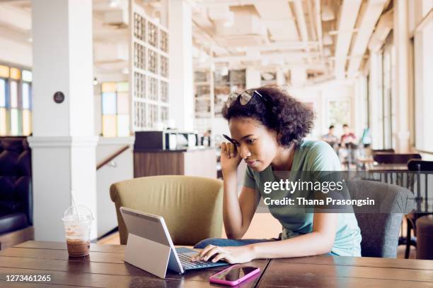 attractive young woman working on laptop and taking notes - student ipad stock-fotos und bilder