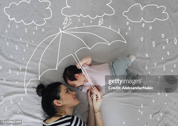 mama wird dich vor zukünftigen stürmen retten - mother protecting from rain stock-fotos und bilder