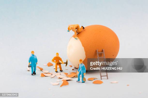 peeling off the hard egg shell. figurines work hard - hard boiled eggs stock-fotos und bilder