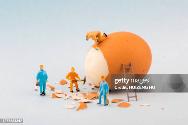 peeling off the hard egg shell. figurines work hard - figurine bildbanksfoton och bilder