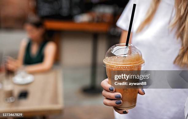 frau hält plastikglas eiskaffee - iced coffee stock-fotos und bilder