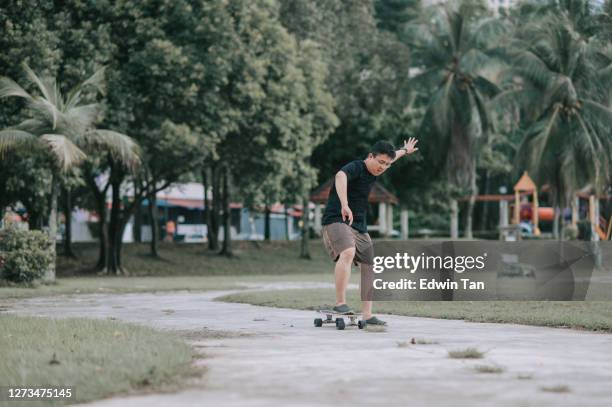 aziatische chinese midden volwassen mens die leert skateboarden bij openbare parkweekendochtend spelen - new challenge stockfoto's en -beelden