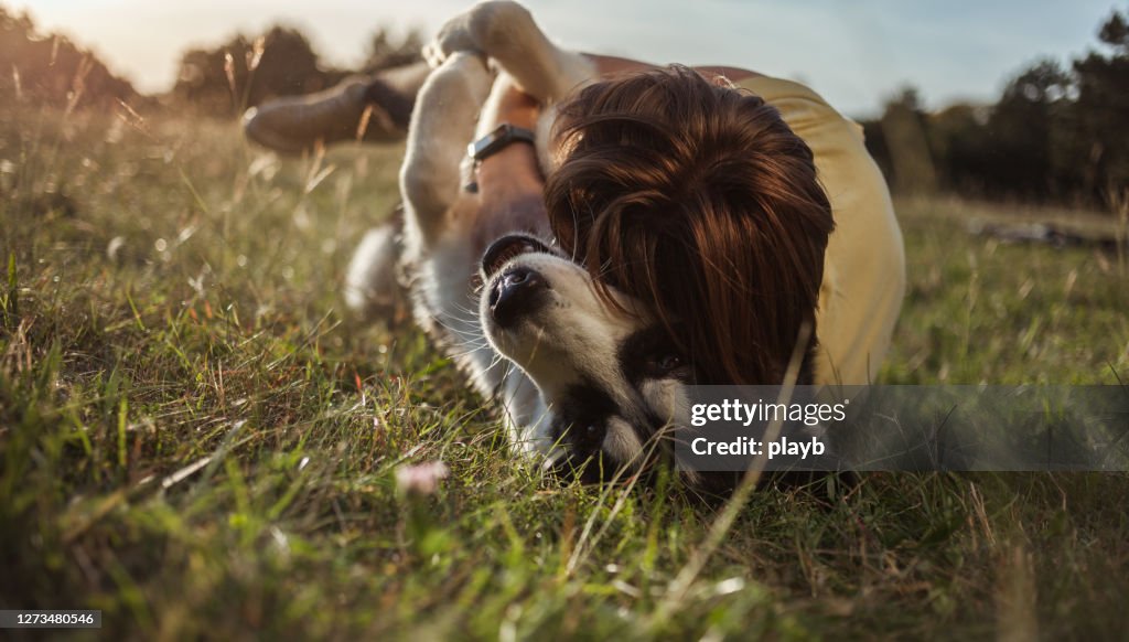 Teenage girl playing with Husky dog outdoors