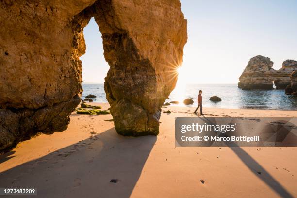 person walking among limestone rock formations, algarve, portugal - distrito de faro portugal fotografías e imágenes de stock