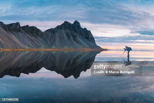 photographer standing on a mirroring layer of water, iceland - symmetry stock pictures, royalty-free photos & images