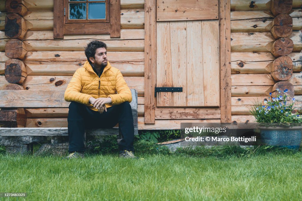 Man sitting on a bench in a mountain hut, Romsdal valley, Norway
