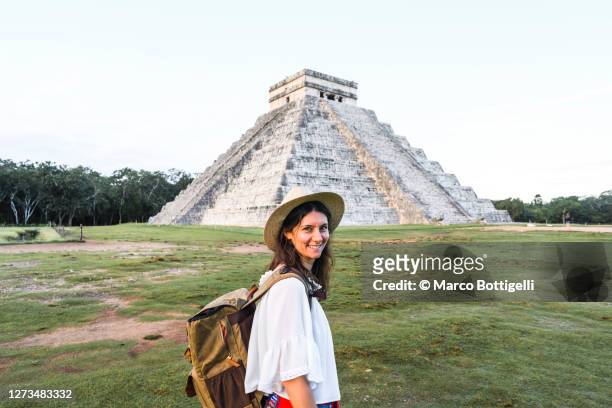cheerful woman tourist looking at camera in chichen itza archaeological site, mexico - monument stockfoto's en -beelden